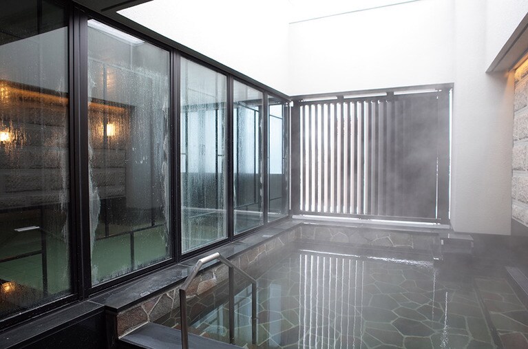 女湯は眺望がないが露天風呂がある。右の壁の石は、オリジナルの建物に使われていた小樽軟石。