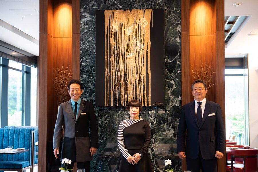 「リージェンシークラブ」に飾られた作品を前にコシノジュンコさん(中央)、コシノさんがデザインしたホテルの制服を身にまとった辰巳琢郎さん(左)、ホテルを開業させた相互物産グループの小澤真也代表。