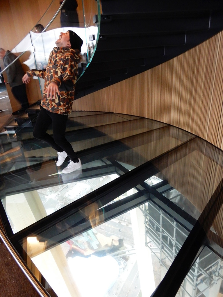 回転レストランフロアーのガラスの床で動画を撮影中の方。