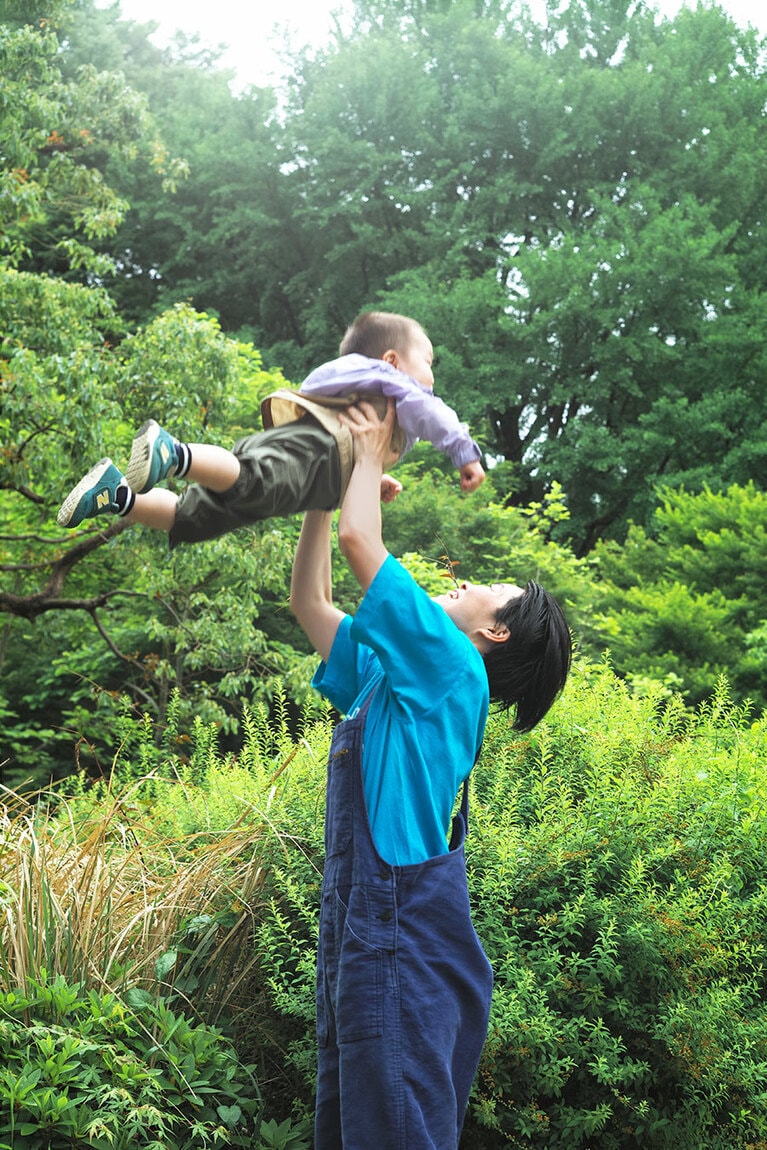 巻頭グラビアより。息子さんをダイナミックに「高い高い」するイモトさん。
衣装：イモトさんTシャツ（古着） 4,950円、サロペット（古着） 9,790円／ともにサンタモニカ表参道店 babyカーキサロペット 7,150円、ラベンダー×ケルプタン フード付きJK 7,150円／ともにザ・ノース・フェイス（ゴールドウイン カスタマーサービスセンター）、靴、靴下／本人私物