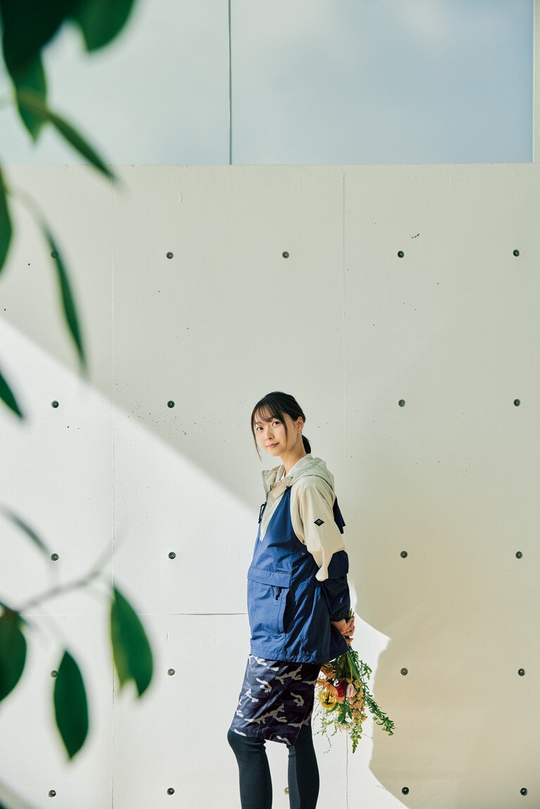 ネイビーを基調としたスポーティなコーディネート。2トーンのアノラックパーカは、コットンナイロンにポリウレタンを混紡したオリジナル素材を使用。コットンのようにナチュラルな風合いながら、ストレッチ性にも長けている。背裏はメッシュ仕様。さらに脇下にはベンチレーションも備え、通気性も抜群だ。両裾にドローコードを配し、シルエットのアレンジも自在。ボトムスにはオリジナルのカモ柄をのせ、格子調にエンボス加工を施した立体感のあるベルト付きショーツを。エンボス加工はデザインの表現だけでなく、汗がベタつきにくい肌離れのよさにも寄与。裏地にはメッシュを用い、清涼感のある履き心地に。パーカ 26,400円、ショーツ 19,800円。