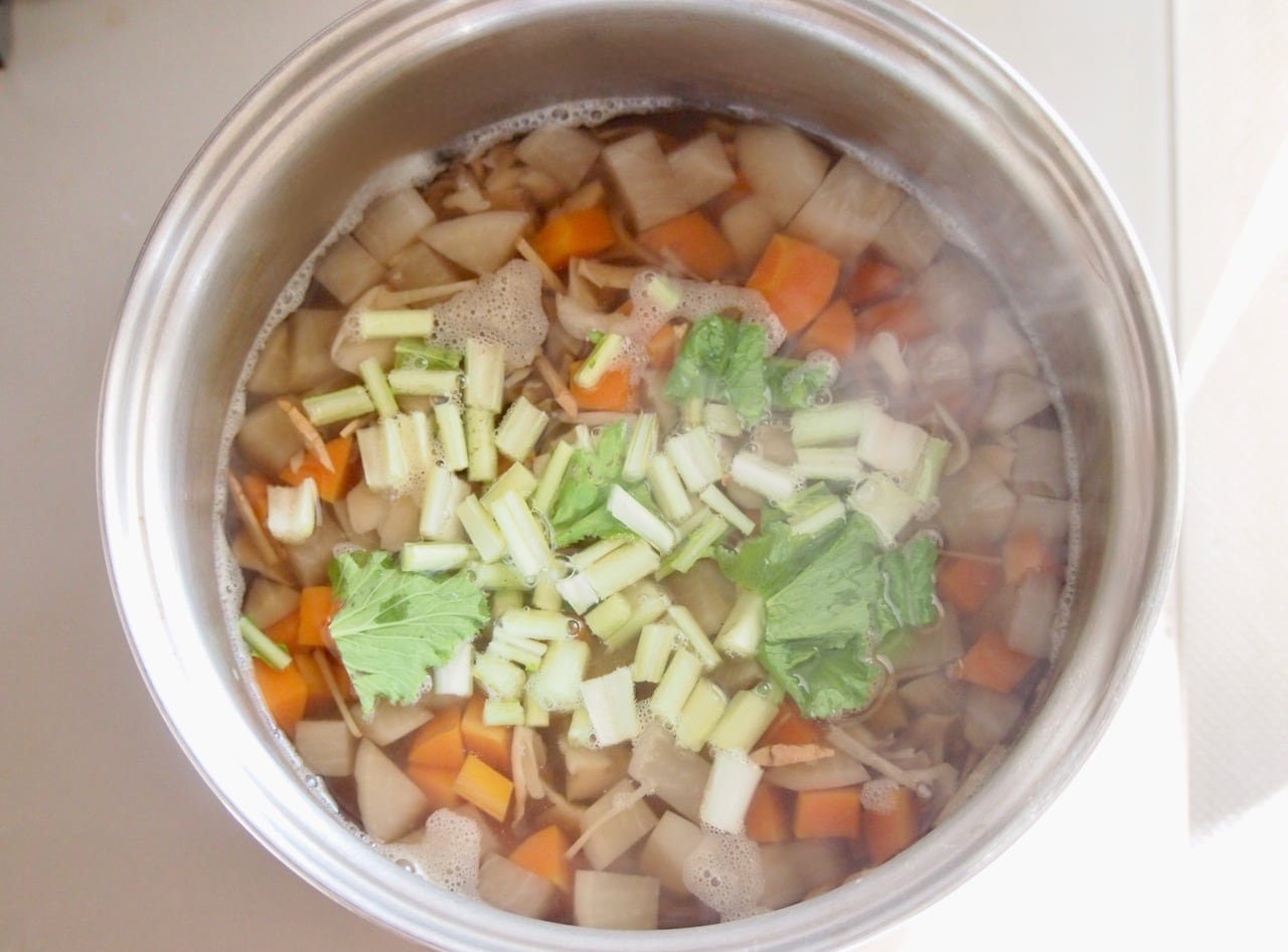 野菜がやわらかくなったら塩、醤油で味を調え、刻んだカブの葉を散らす。