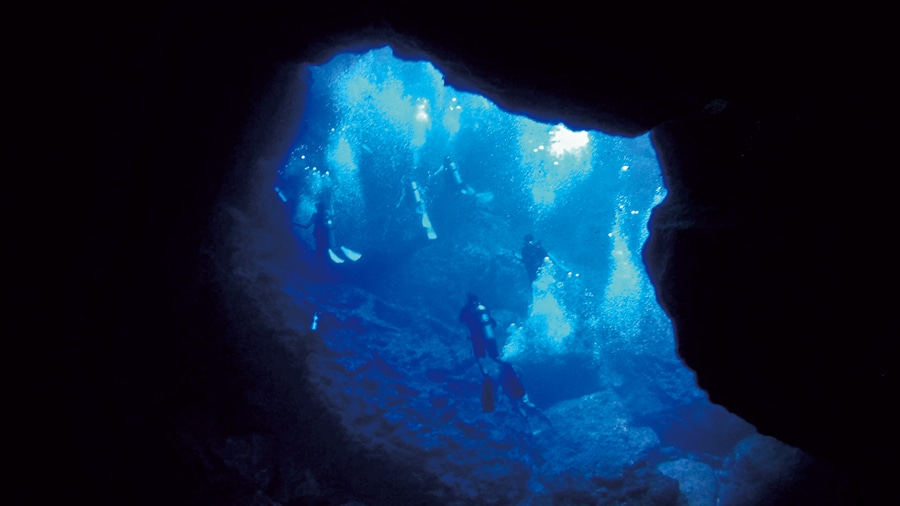 サイパン島の海底洞窟グロットでダイビング。横穴から差し込む光によってディープブルーに輝く水中の光景は神秘的。