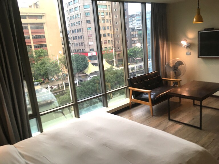 デラックスダブルルーム。壁備え付けの液晶テレビと木目で落ち着くデザインのソファーも完備。