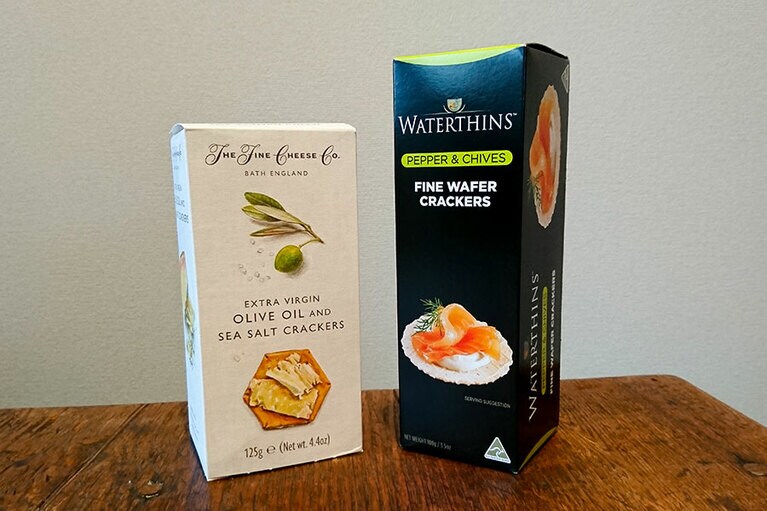 クラッカーも薄めを。左：香ばしさがいい！　オリーブオイル アンド シーソルトクラッカーズ 125g 600円／ザ・ファインチーズカンパニー。右：編集部員イデミも愛用。ファインクラッカーペッパー＆チャイブ 100g 450円／ウォーターシンズ。