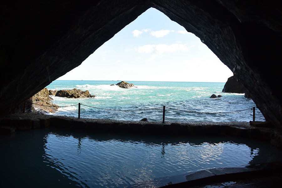浸食された岩壁で三角に切り取られた熊野灘を望む、ホテル浦島の温泉「忘帰洞」。
