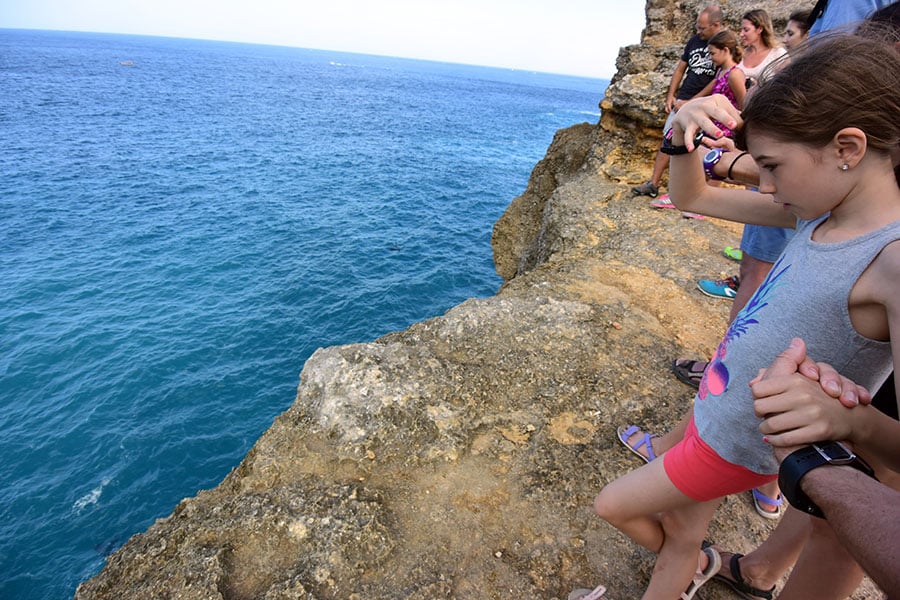 「マンタ・ベイ」の断崖からおそるおそる海を覗く女の子。