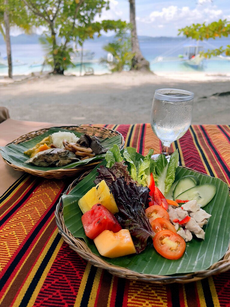 木の枝で編んだお皿にヤシの葉を敷いて、白いビーチと青い空を眺めながら、フルーツたっぷりのランチ。