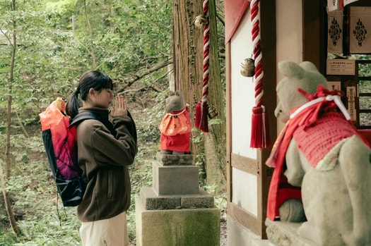 鳥居をくぐると、迫力満点の寳登山神社本殿が出迎えます。本殿奥には、倉稲魂命（うかのみたまのみこと）を祀る宝玉稲荷神社が。お稲荷さまにお参りすると、なくしていたものが見つかるとも言われています。菊池さん着用：ターギー フォー ミッド ウォータープルーフ ¥24,200、ジャケット ¥14,300／ともにキーン（キーン・ジャパン）、zipトップス 11,000円／マーモット（サードシップ）、パンツ 30,800円／ワイドット（NORDISK APPAREL）、バックパック 59,400円／ライトエーエフ（バンブーシュート）