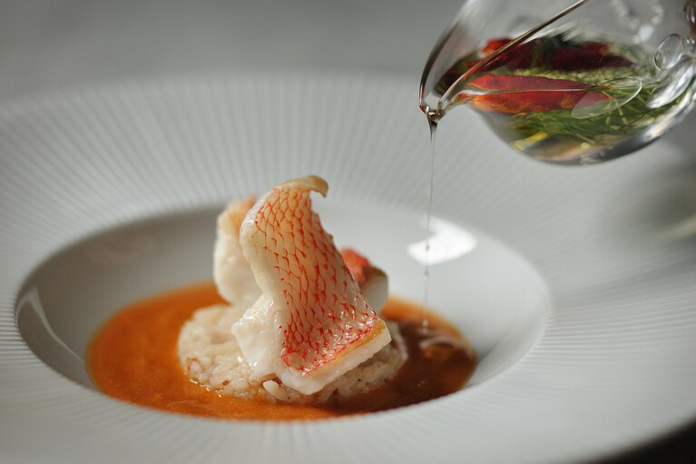 「キンキとカニのチュッピン」という魚料理。魚介の風味と濃厚なスープを楽しむ一品。