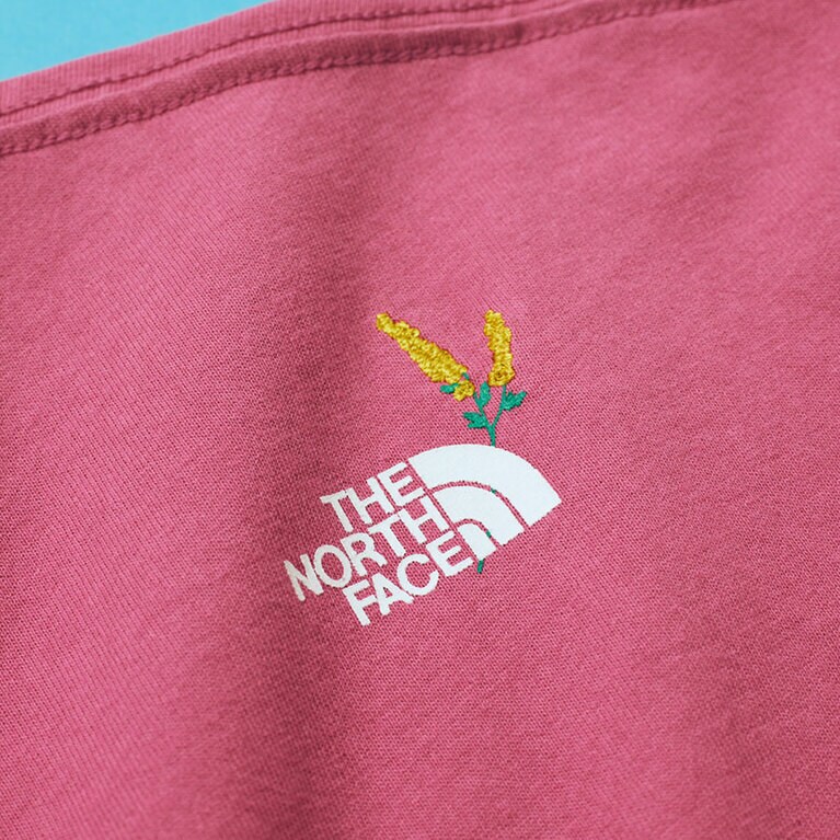 右肩背面にプリントされたザ・ノース・フェイスのロゴとミモザの刺繍。