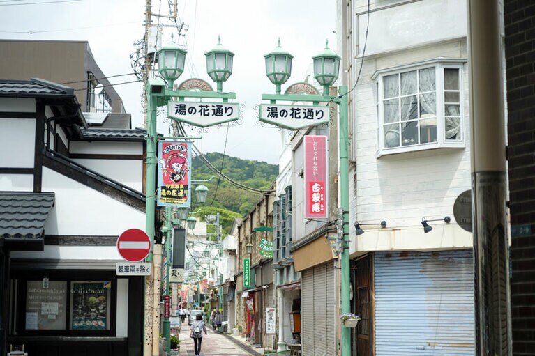 駅から歩いてすぐの湯の花通り商店街は、みやげ物店、食事処、カフェなどが軒を連ねる賑やかなエリア。点在する「お湯かけ七福神」に湯をかければ願いが叶うとか。