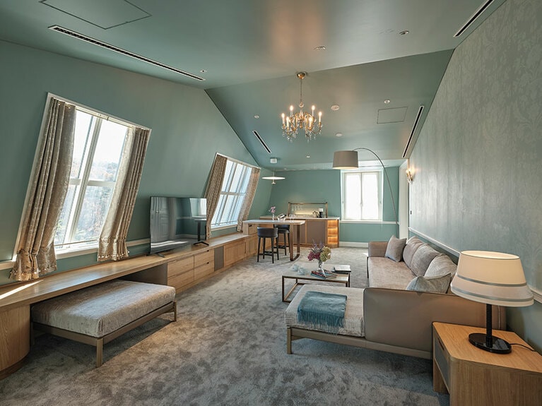 客室の一例「スイートルーム#31」のリビングスペース。屋根の傾斜に合わせた斜めの壁や天井、屋根窓などが特徴的。