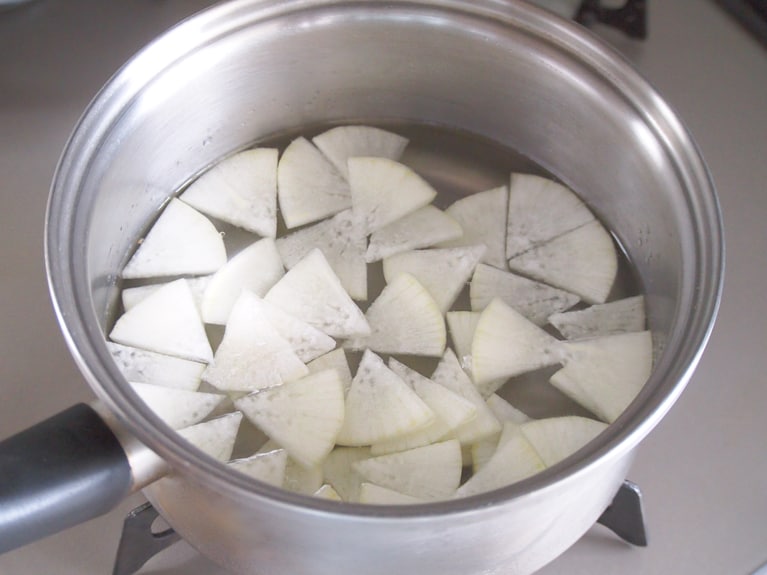 手鍋にだし汁を入れ、（1）の大根、蕪を入れて煮る。蕪の葉の部分は仕上げに入れるのでとっておく。