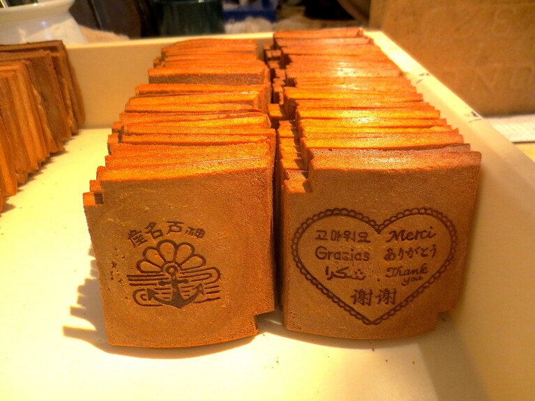 焼きたての瓦せんべい。右は「えみり堂」オリジナル。各国語の「ありがとう」。左は、神戸らしい錨のマーク入り。