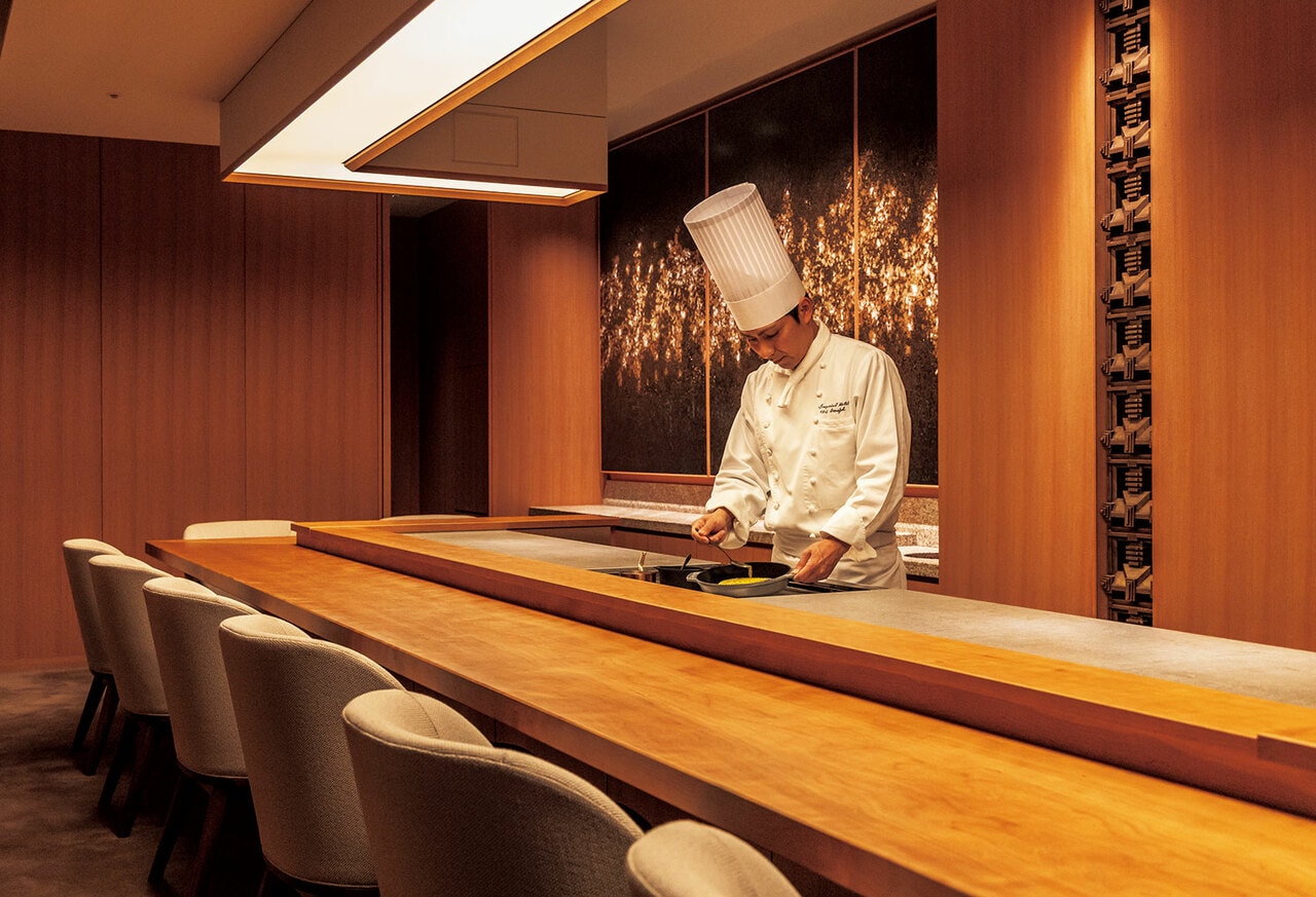 フランス料理「練」のカウンター内で腕をふるう今城浩二料理長。背後には左官のアートワークが。