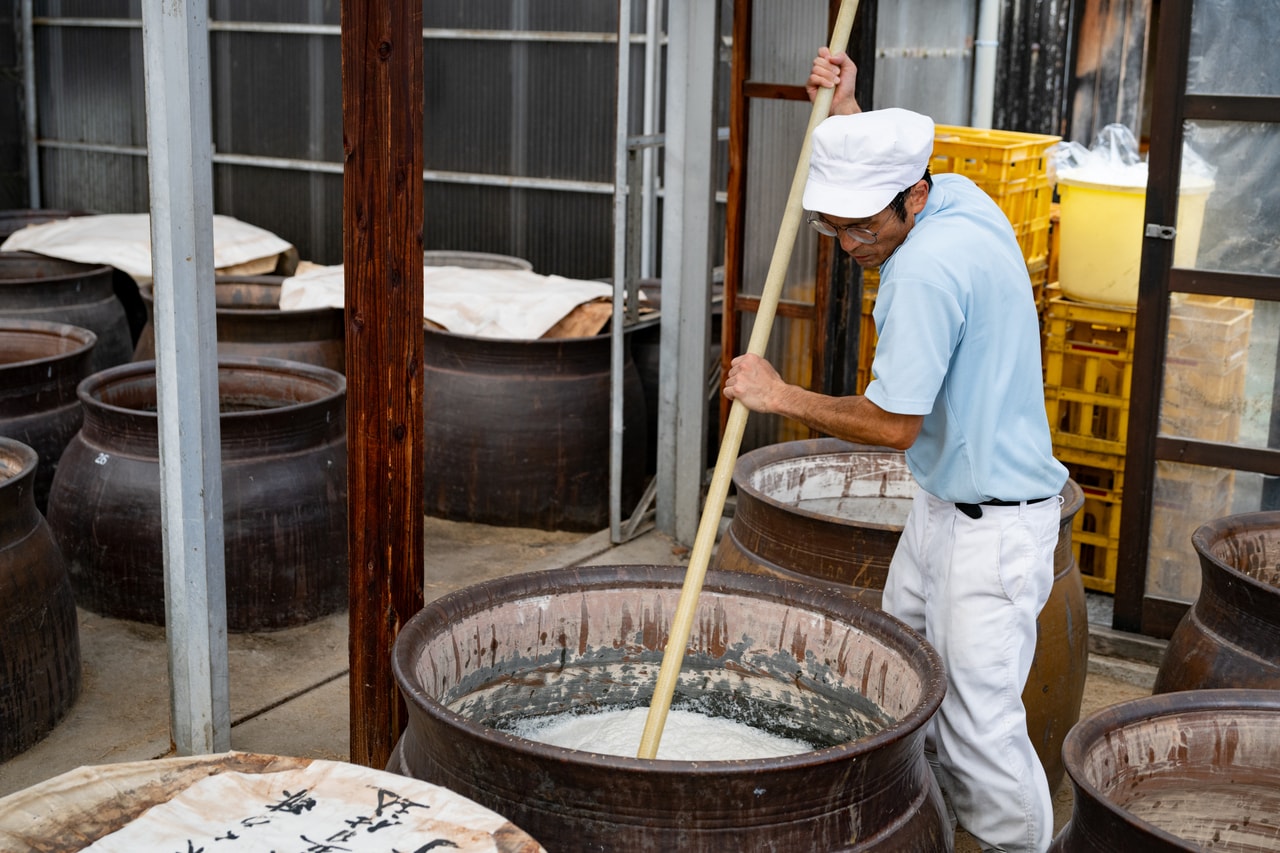 蒸した玄米、水、米麹を甕の中で混ぜ合わせる。