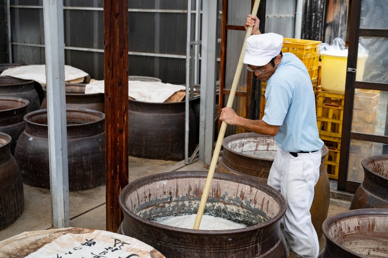 蒸した玄米、水、米麹を甕の中で混ぜ合わせる。