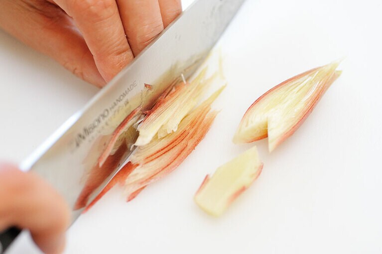 みょうがのせん切りは、まず縦半分に切り、芯をV字の逆の形にカットして、縦に細く切ります。