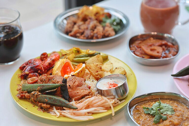 エッグ・ナシカンダール 1,200円。スパイスオイルに漬け込んだ半熟卵、ココナッツミルクでマイルドに仕上げたイカカレーは素揚げのエビ付き。手前右はひよこ豆のダール・フライ(追加は450円)。