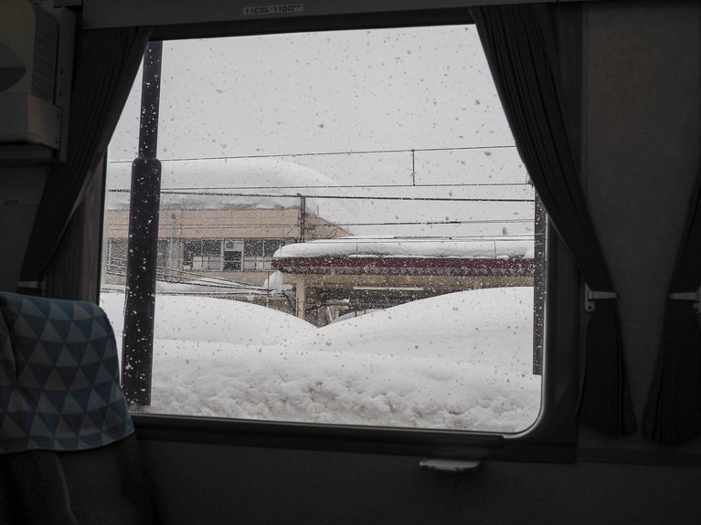 「 研ぎ澄ます、雪の妻有」 ⼭本 茜  「車窓からの雪景色」 ほくほく線の車内からの景色。どの建物も大きなぼた餅をかぶっているかのよう。列車は安定した速度で進む。