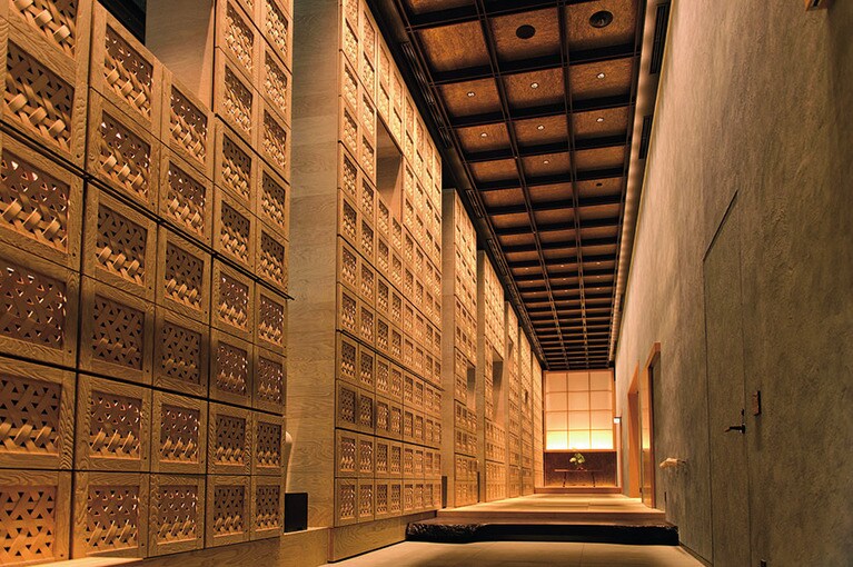 【星のや東京】青森ヒバの一枚板でできた扉を入ると、そこには広々とした和空間が待っている。壁一面の竹細工は、なんと靴箱。畳を裸足で歩くのが星のや東京のステイスタイルだ。Photo: Wataru Sato