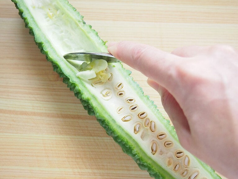 (1) ゴーヤは縦半分に包丁で切り、中のワタをスプーンで取り除きます。