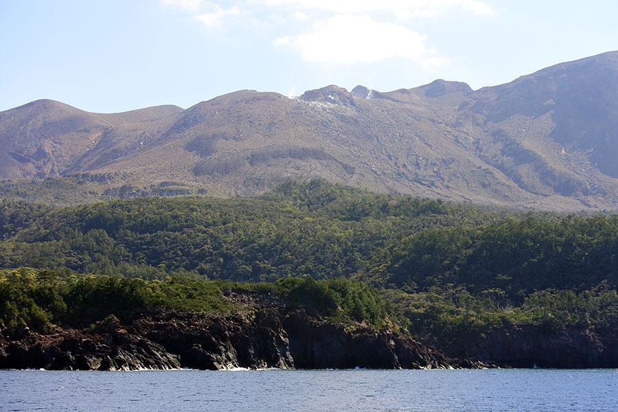 1000年前から活動が始まり、今も煙を噴く新岳。山頂付近は噴火の影響で岩が露出しているけれど、麓には緑が。