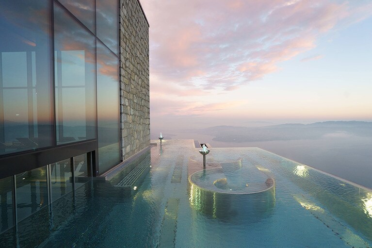 「アルパイン スパ」のメインプールはガラス張りで、屋内から屋外へと続いていて、打たせ湯などのハイドロスパ施設も備わっている。