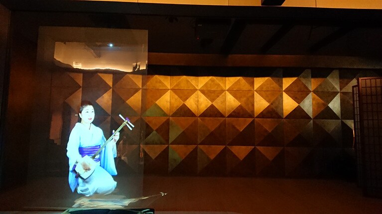 プロジェクターで舞台上に映し出される芸妓さん。