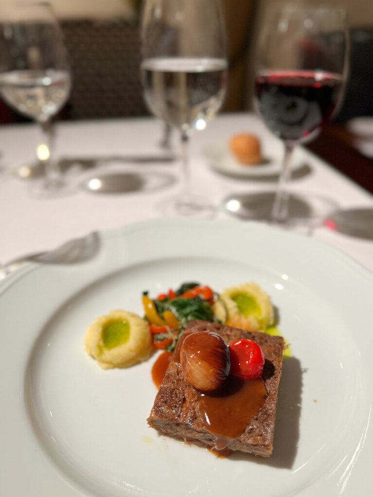 この日のコースのメイン料理はビーフソテー。小さな玉ネギとミニトマトが載っている。付け合わせはセロリ入りポテトクリーム、ほうれん草に似た青菜のソテー。