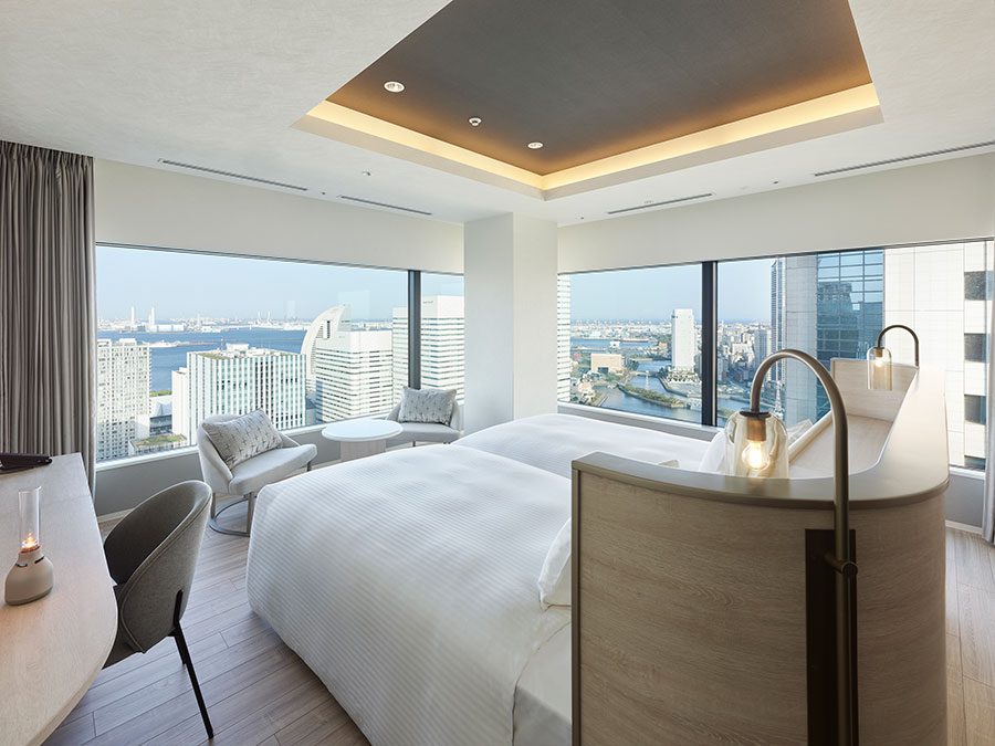 客室の一例。窓から横浜の海や街、空と一体になるような眺望を味わえるようにと、ベッドの向きにも配慮した「エグゼクティブコーナーツイン」。