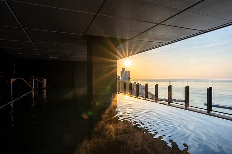 天空の船をイメージしたという、全長12mのインフィニティバス。海に向かって溢れ落ちる荘厳な湯音は、波を割って進む船を思わせる。