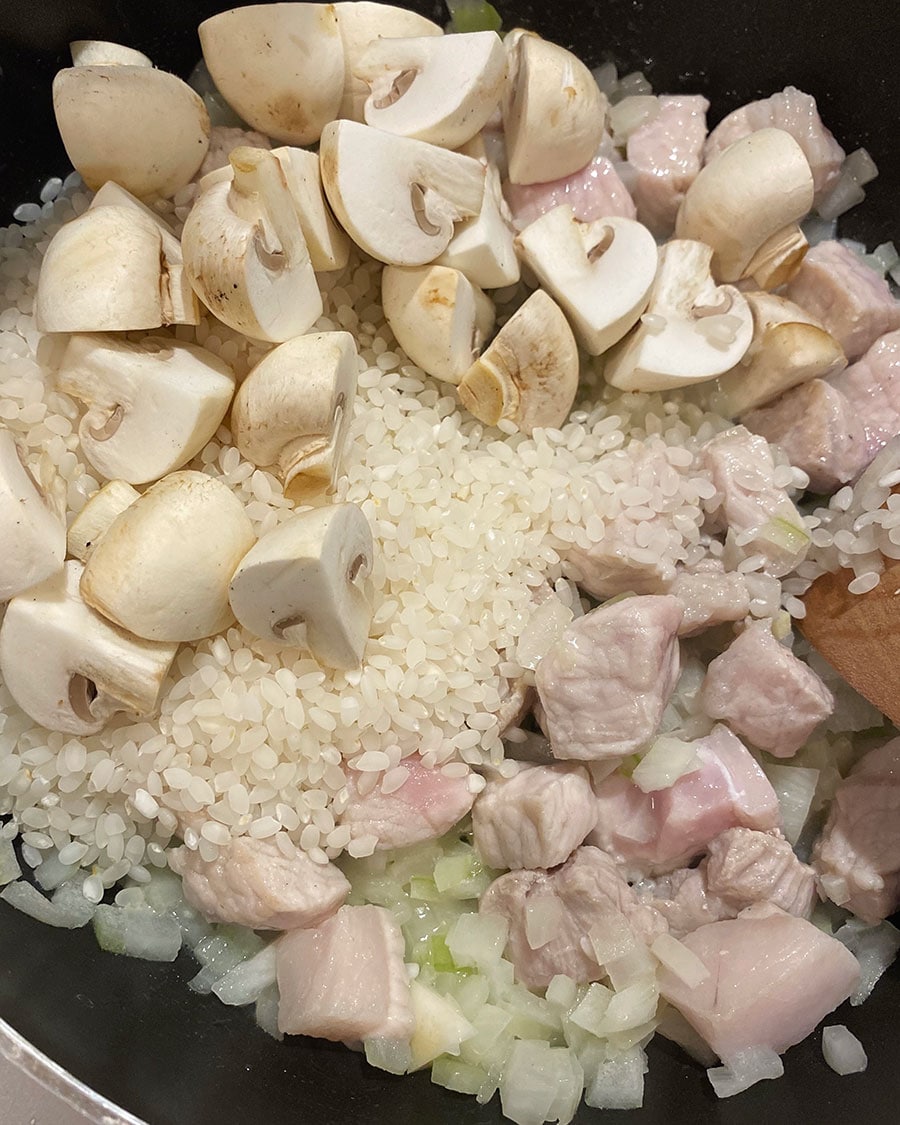 【ごろっと豚肉とマッシュルームのパセリバター炊き込みごはん】(5) お肉の色が変わり、玉ねぎが透き通ったら、マッシュルームと米を加えて米が透明になるまでさらに炒める。
