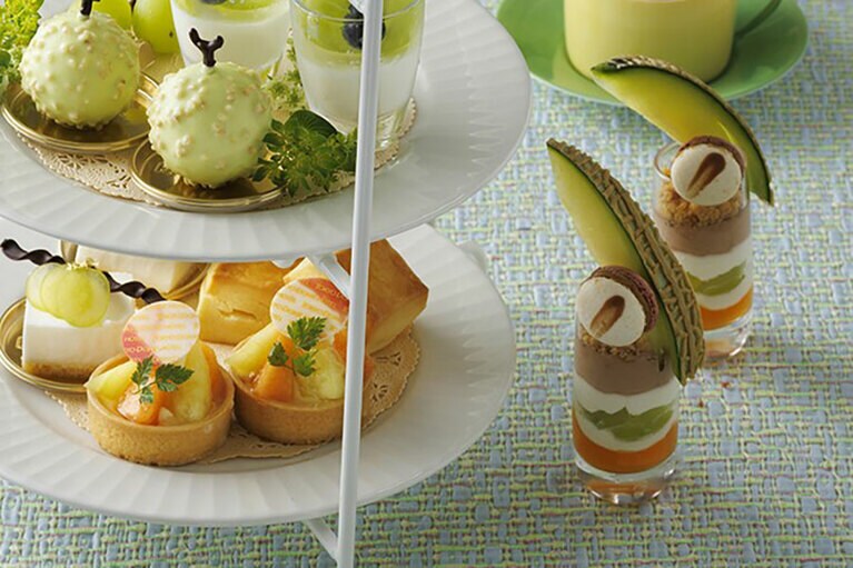 写真右、シェフこだわりのスイーツ「シャインマスカットとメロンのパフェ・本日のマカロン」。