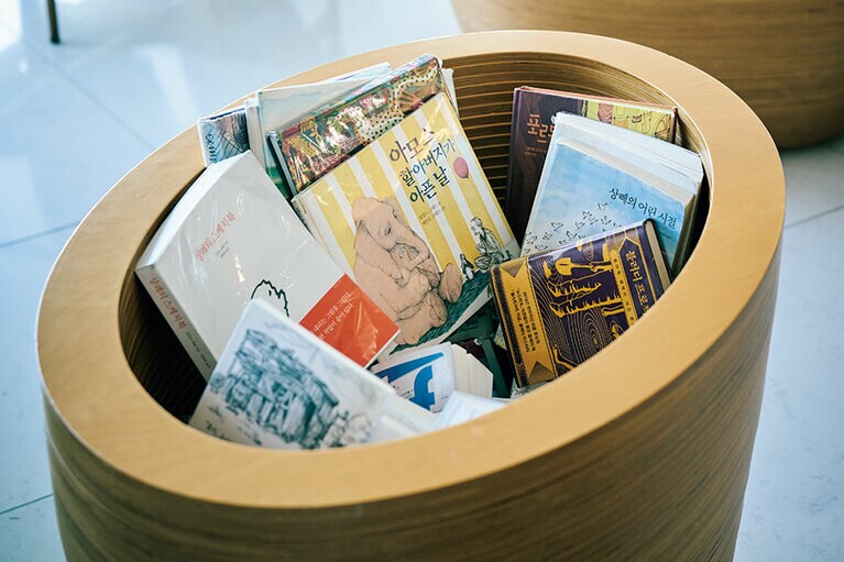 ウッドボックスに入った本で試し読みして購入する仕組み。入り口すぐはカフェスペース、奥の受付で企画展の入場券を販売。