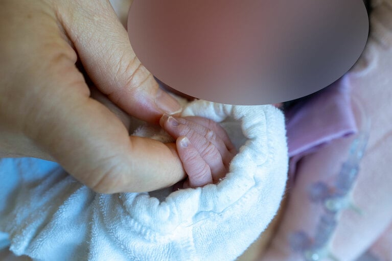 小さな手を握る上田さん（本人提供）