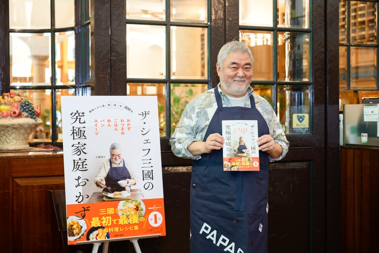 新刊を手に微笑む三國シェフ