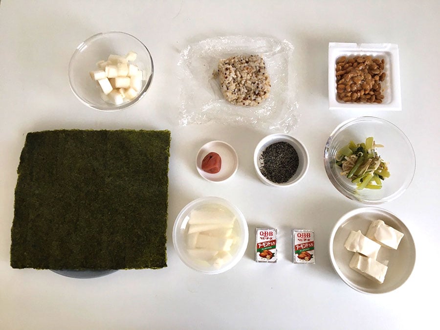 左下から時計回りに、のり、酢大根、ご飯、納豆、青菜ともやしのお浸し、水切り豆腐、チーズ、スティック大根、梅干し、すりごま。