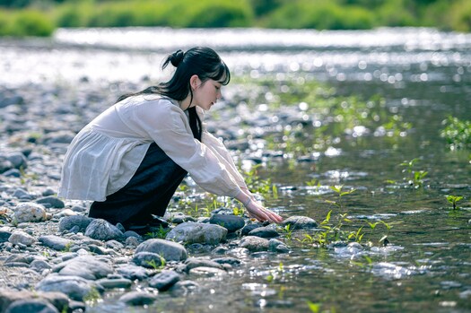 豊かな自然に恵まれた、徳島県美馬市。市を囲む山は季節ごとに姿を変え、春は桜、夏は新緑、秋は紅葉、そして冬は雪化粧をした姿も。リネン天然染めギャザーブラウス（OFF WHITE）30,800円、リネンデニムワイドジーン（BLACK）33,000円