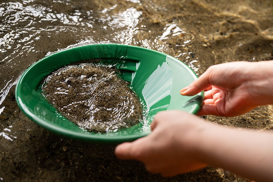 水中で砂利をゆすって砂金を下のほうに沈殿させたら、上部の砂を取り除いていきます。