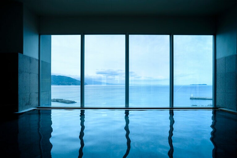 窓を大きく取った大浴場。相模湾の向こうにぽっかりと浮かぶ初島。左手には熱海の街が見える。