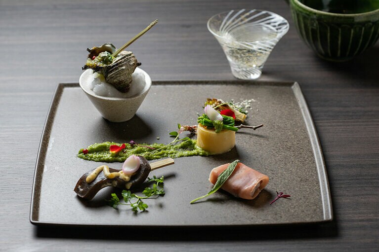 ～前菜～ 上州麦豚とセージのサルティンボッカ風（右下）、群馬蒟蒻の田楽　セルフィーユ香るクリーム味噌（左下）、姫栄螺のブルゴーニュ風　バジルの香草バターで（左上）、芽キャベツのオーブン焼き　タイム風味のチーズを併せて（右奥）、菜の花砧巻き　コリアンダーのチャツネと供に（右上）。