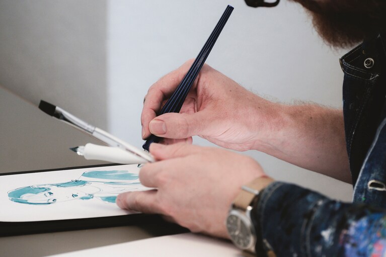 イラストレーターのエイドリアンさんがガラスペンで似顔絵を描く。