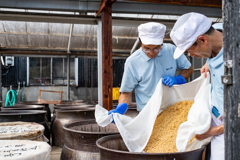 蒸した玄米を冷ましてから甕に入れる。