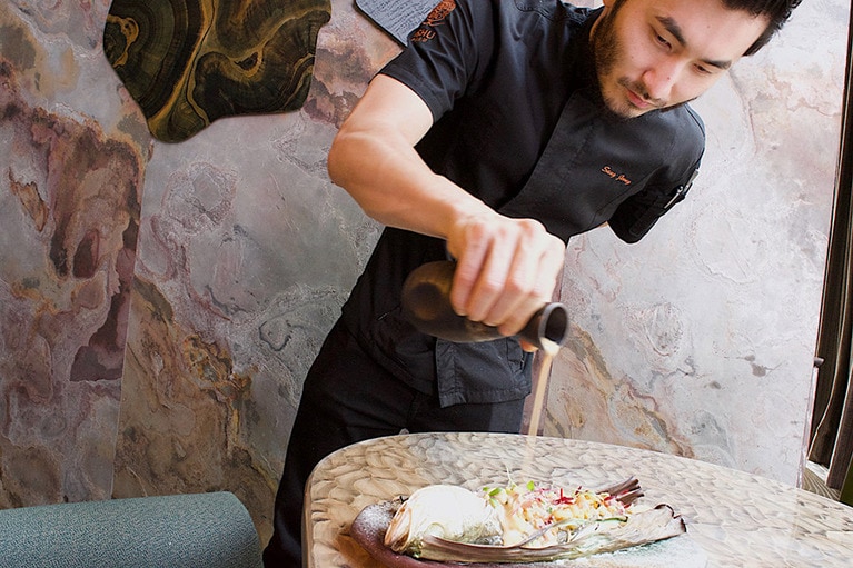 「アマゾンの魚」にソースをかけるシェフ。熱帯雨林で採れるトマトのソースとバナナの葉で包んで焼くのがポイントの料理とか。ジャイアントコーンがたくさん入っていて、この一品も美味しかった。魚はスズキ。420香港ドル。