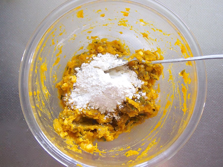 （4）ボウルにかぼちゃを入れて、潰します。茹でた緑豆、コーン缶を入れて全体をよく混ぜ、薄力粉、塩を入れてさらに混ぜ合わせます。