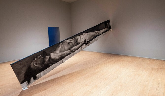 ジョン・バルデッサリが、16世紀の画家ハンス・ホルバインの《墓の中の死せるキリスト》をプリントして部屋を分断。