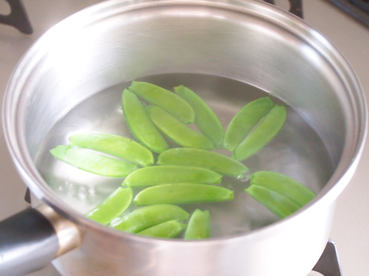 鍋に湯を沸かし、スナップエンドウを茹でる。少し食感が残るように茹で上げて、ザルに入れる。