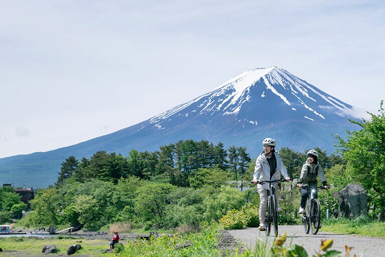 富士山をバックにサイクリングを楽しむ左・映画監督の金子由梨奈さん、右・石川古都さん。